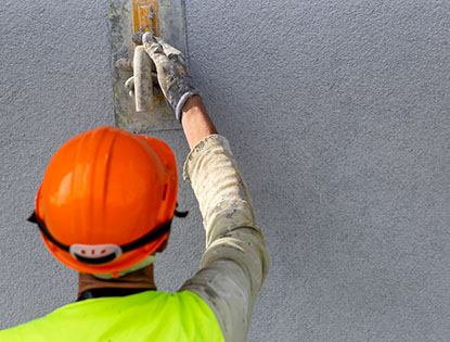 Worker Applying Stucco Finish With Hand Trowel